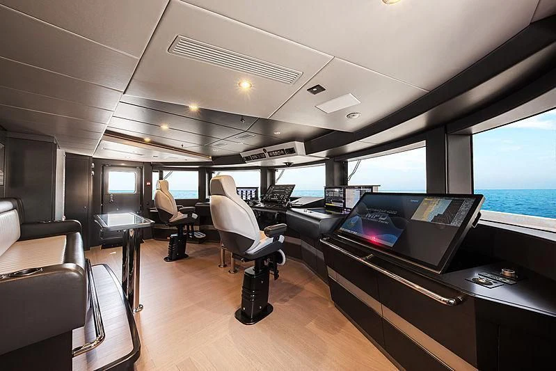 a room with a large window and a couple of people sitting in chairs aboard SPECTRE Yacht for Sale