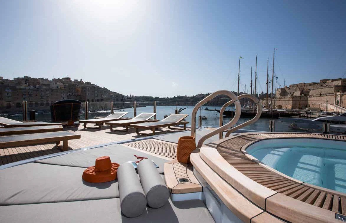 a table with cups on it next to a pool of water aboard GENE MACHINE Yacht for Sale