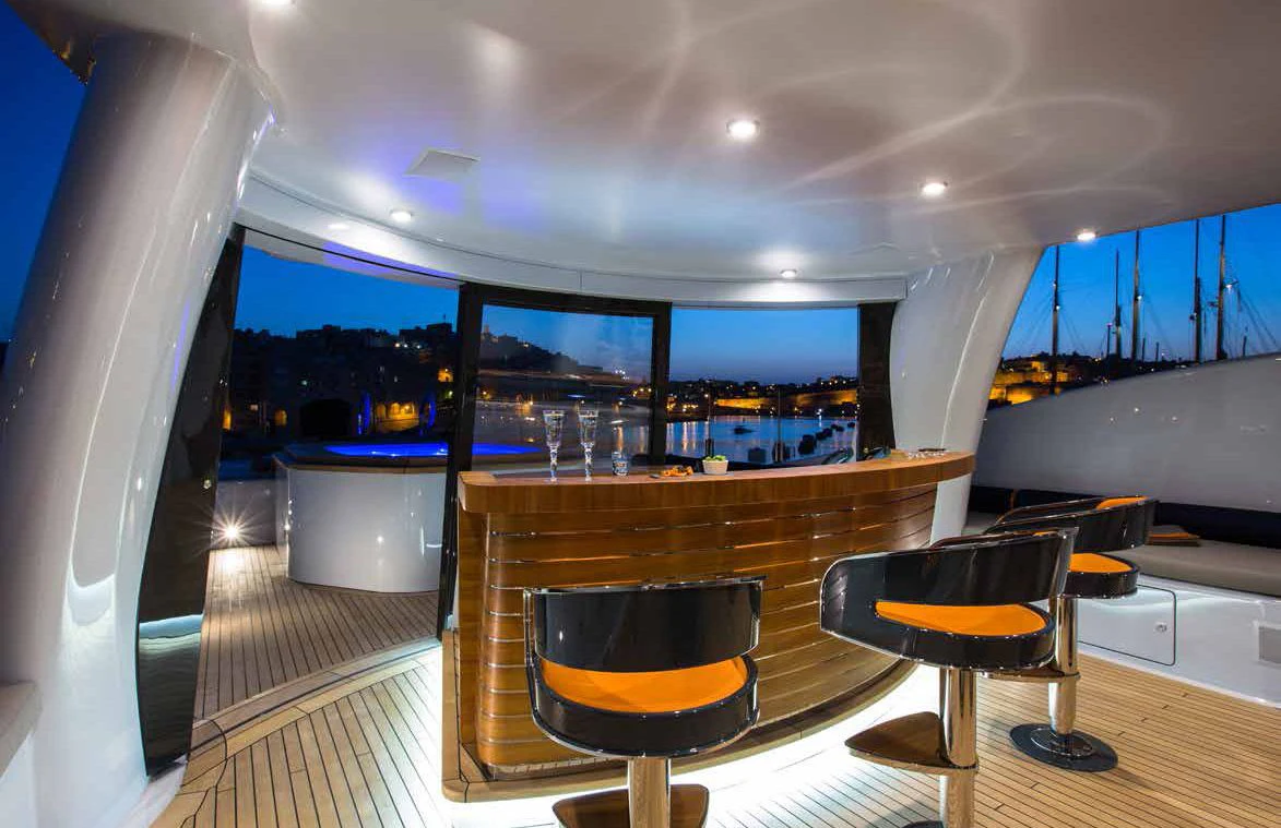 a room with a bar and chairs aboard GENE MACHINE Yacht for Sale