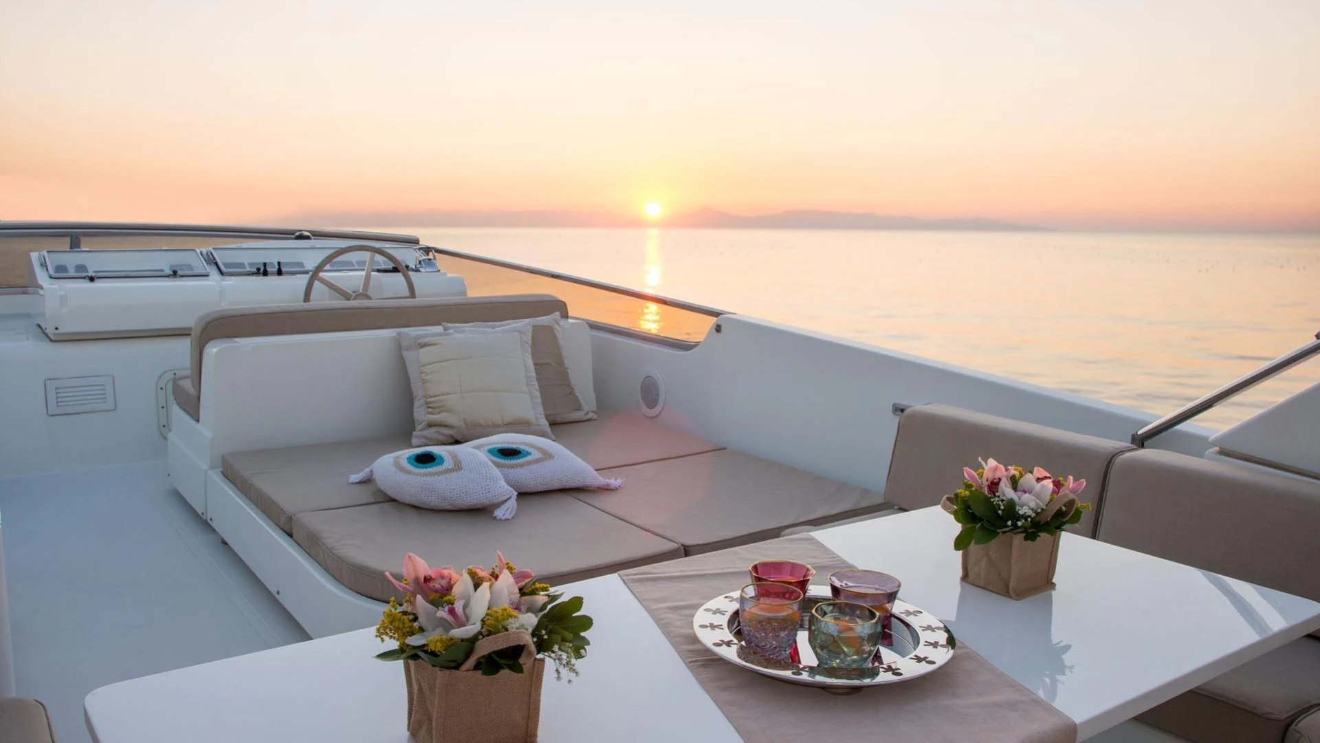 a white yacht with a table and chairs and a vase of flowers aboard ACIONNA Yacht for Sale
