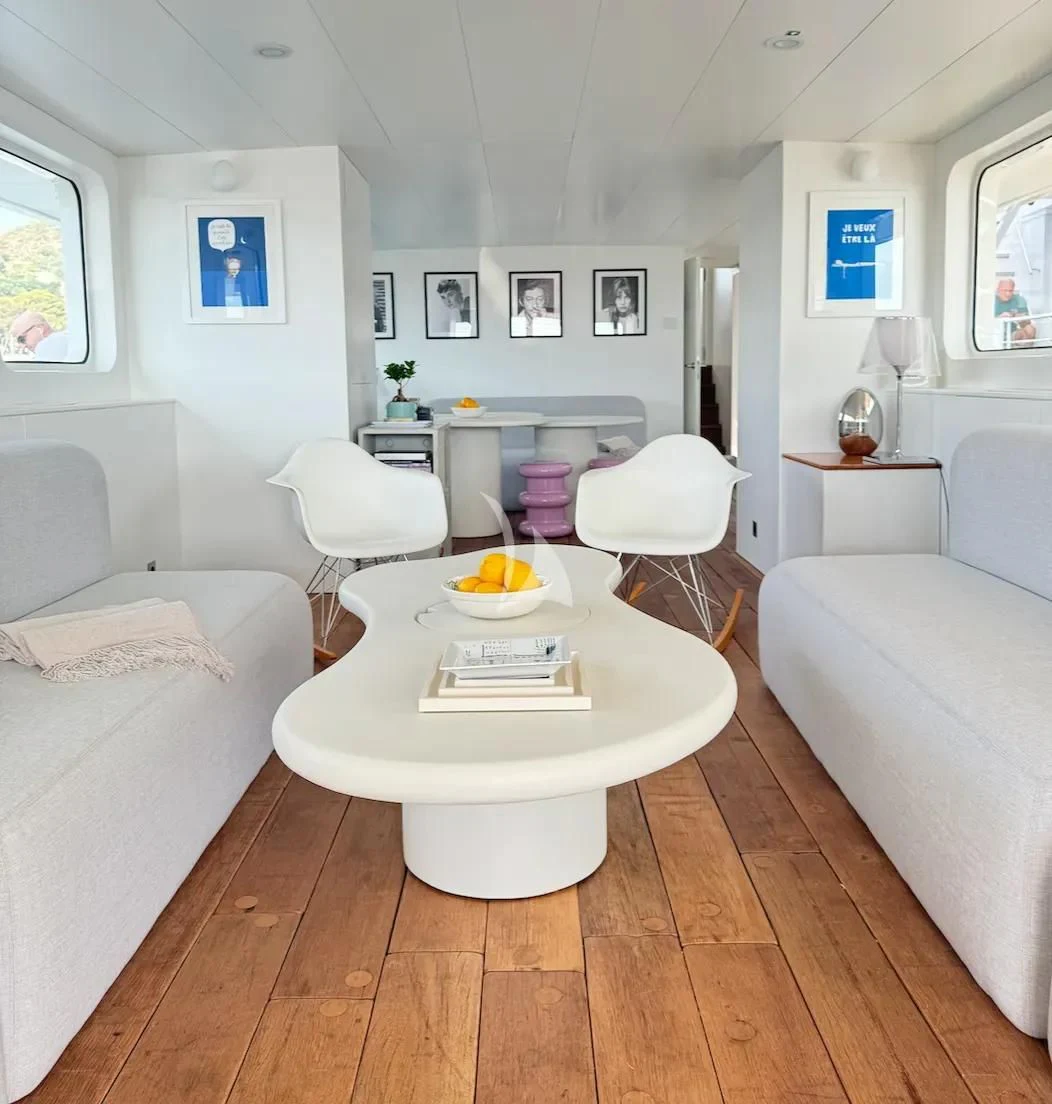 a white living room with a round table and white chairs aboard ABELY Yacht for Sale