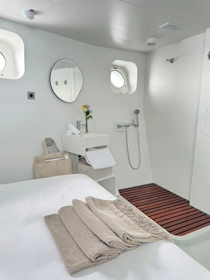 a white bedroom with a red rug aboard ABELY Yacht for Sale