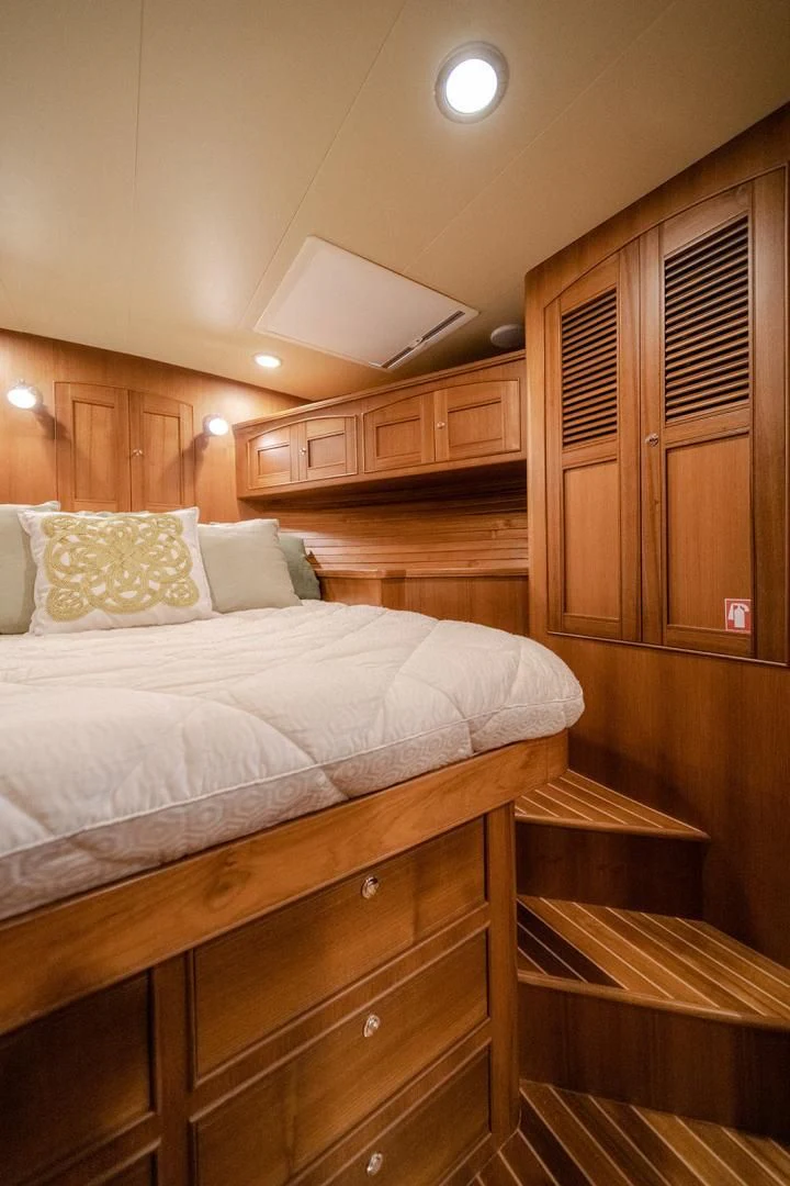 a bedroom with a bed and a wooden cabinet aboard EASYWAY Yacht for Sale