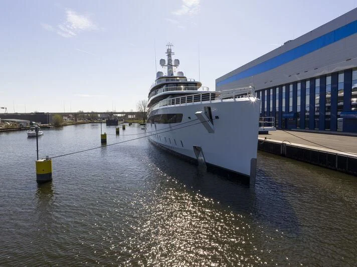 a large white ship docked at a pier aboard DEFY Yacht for Sale