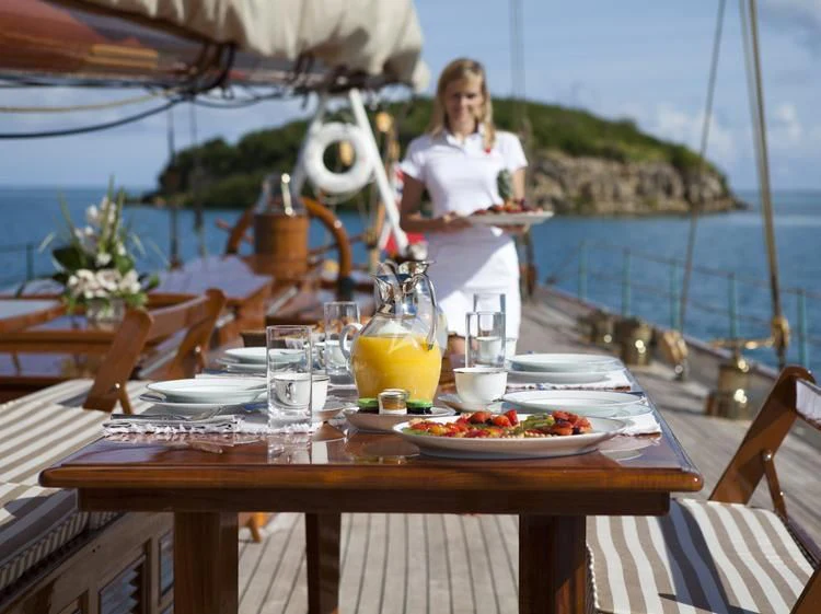 a person standing at a table with food on it aboard ELENA OF LONDON Yacht for Sale