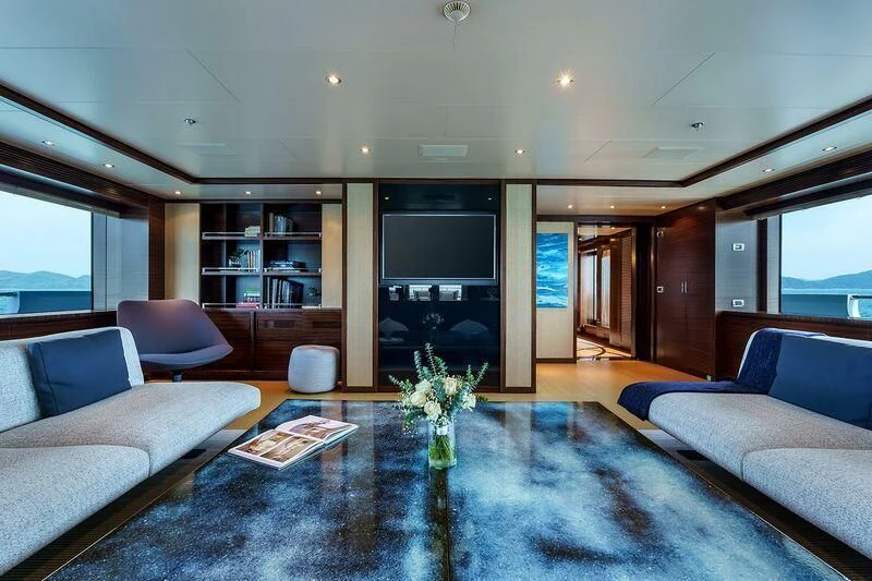 a living room with a large blue rug and a large screen aboard ATLAS Yacht for Sale