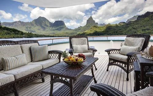 a table and chairs on a deck overlooking a lake aboard ASKARI Yacht for Sale