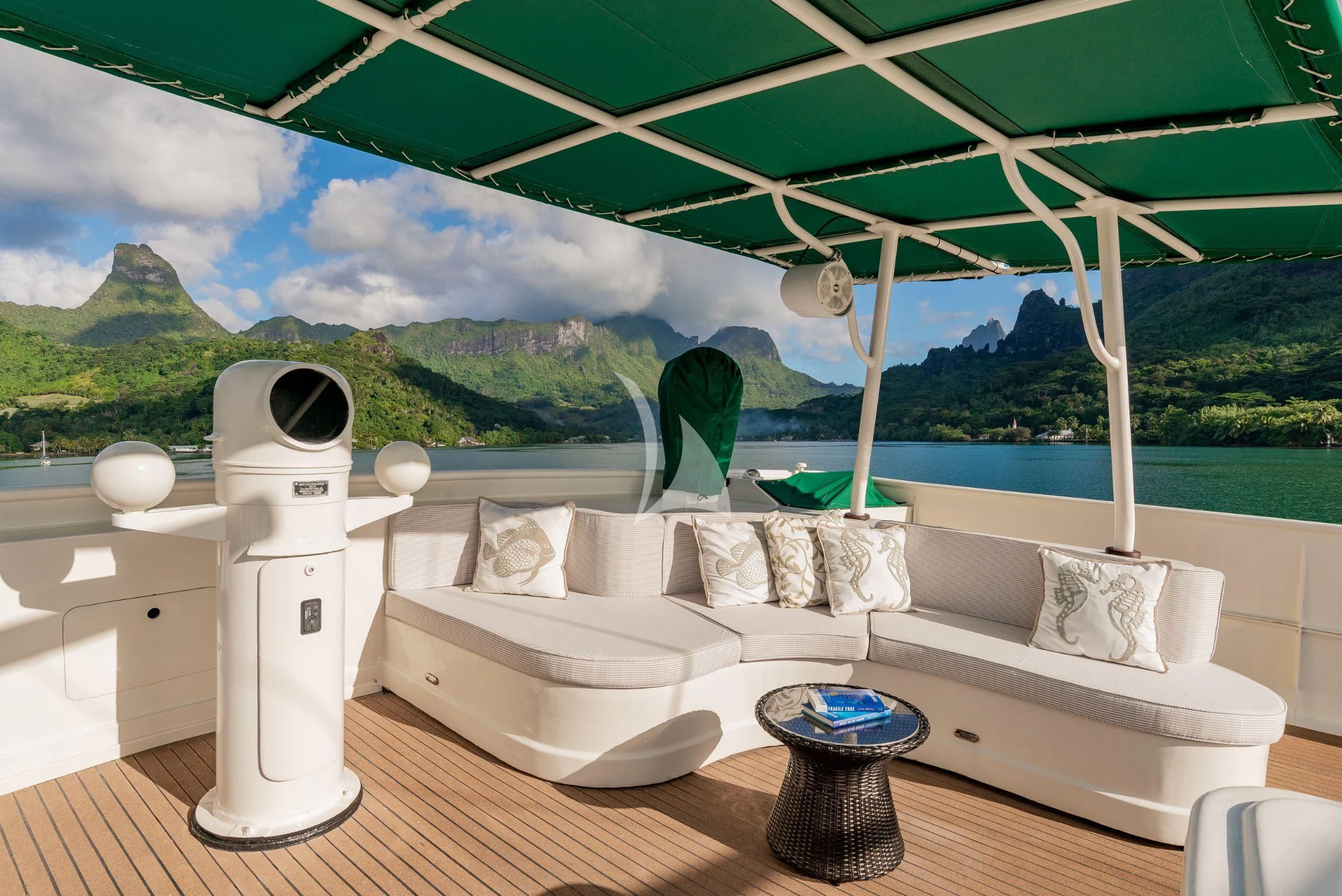 a white couch with a white pillow and a white table with a white chair and a green landscape aboard ASKARI Yacht for Sale