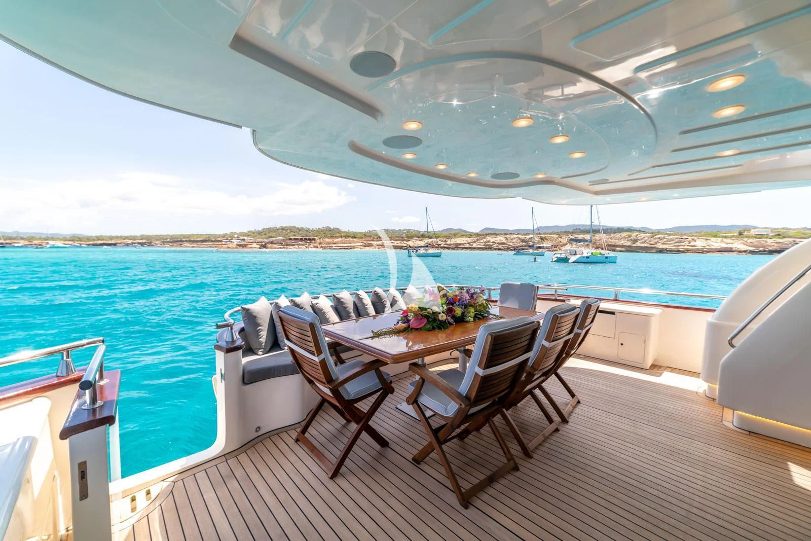 a table and chairs on a deck overlooking a body of water aboard IRMAO Yacht for Sale