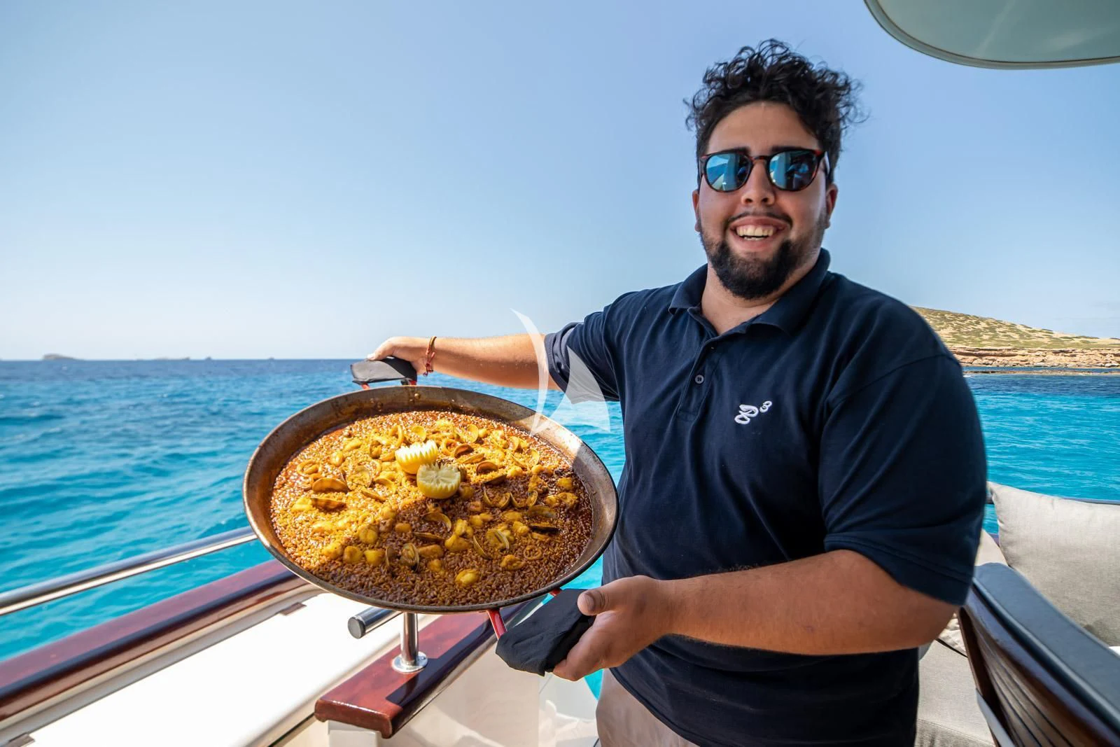 a man holding a plate of food aboard IRMAO Yacht for Sale