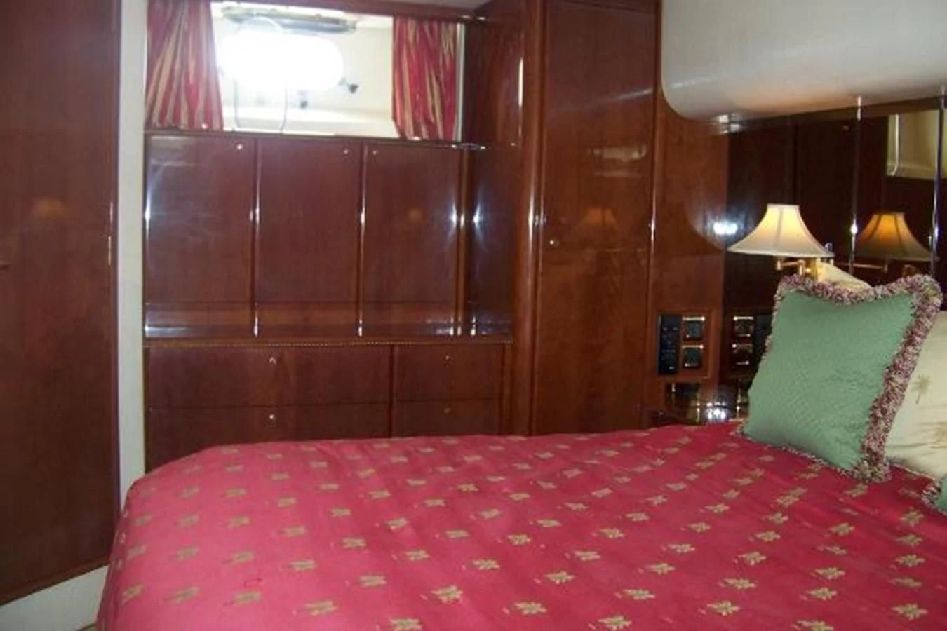a bed with a red and white comforter and pillows aboard KAILANI Yacht for Sale