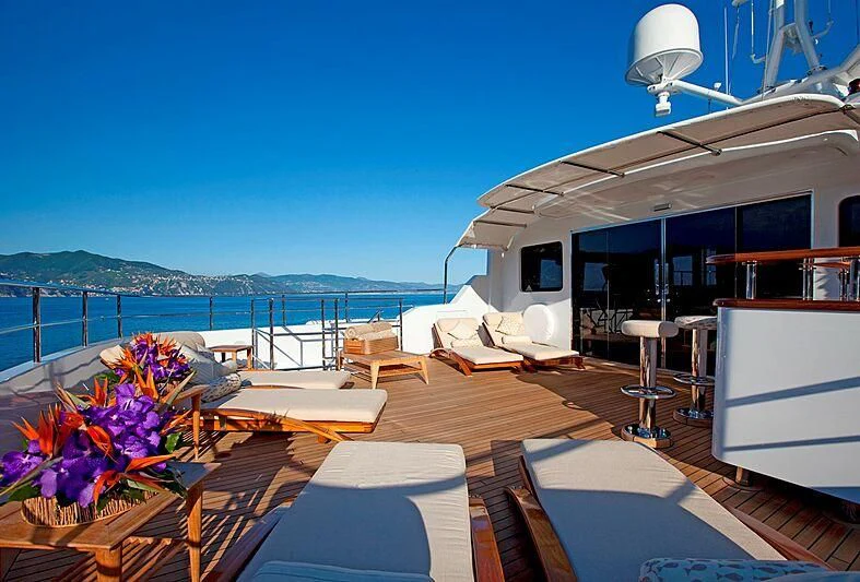 a deck with a view of the ocean and a large boat aboard ELENA V Yacht for Sale