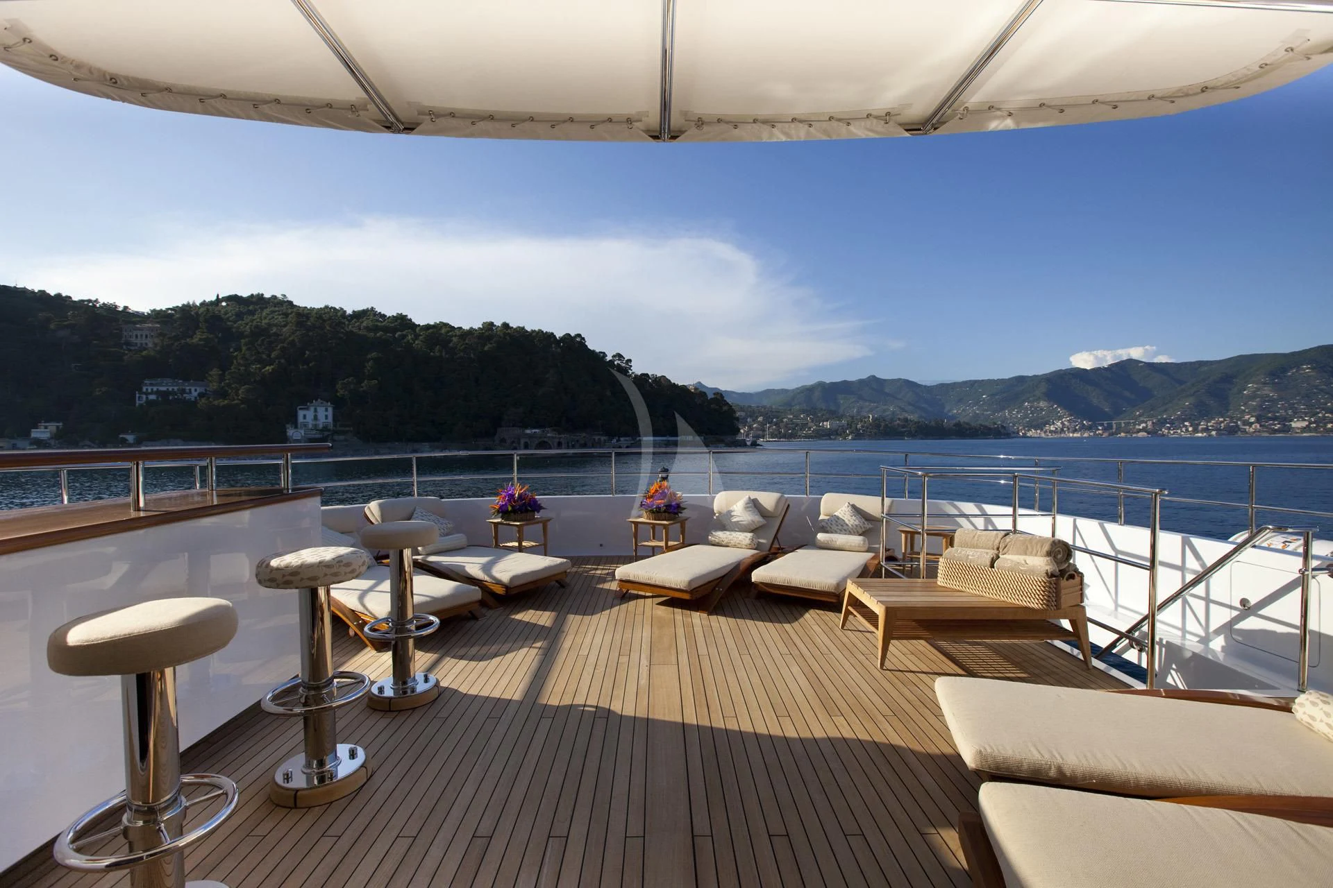 a deck with chairs and tables on it by a body of water aboard ELENA V Yacht for Sale