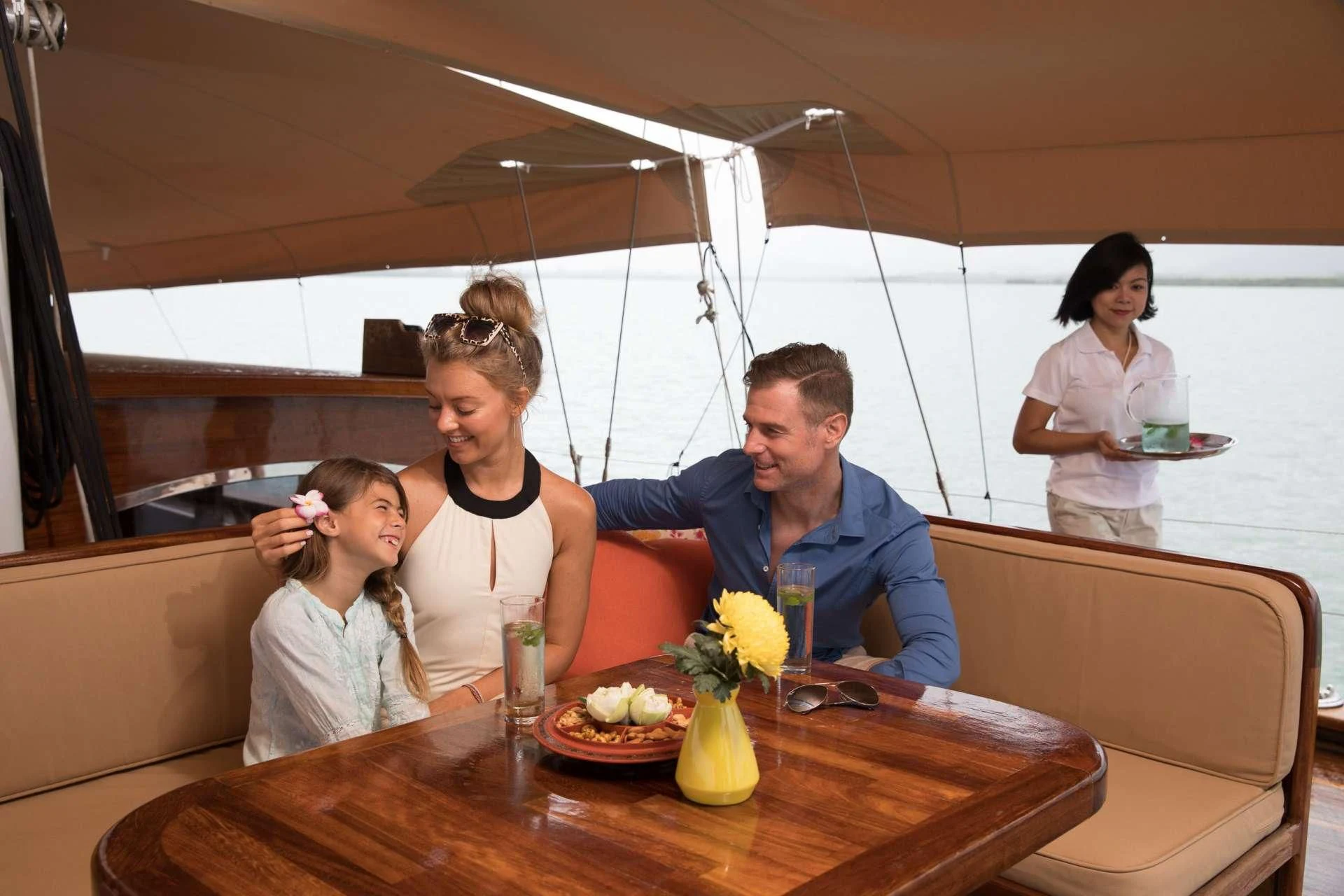 a group of people sitting at a table with food and drinks aboard THE BLUE Yacht for Sale