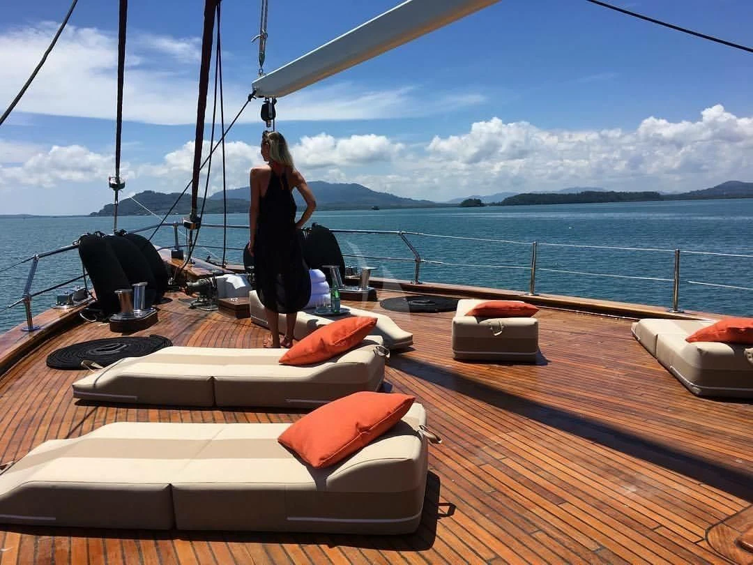 a person standing on a deck looking at a boat on the water aboard THE BLUE Yacht for Sale