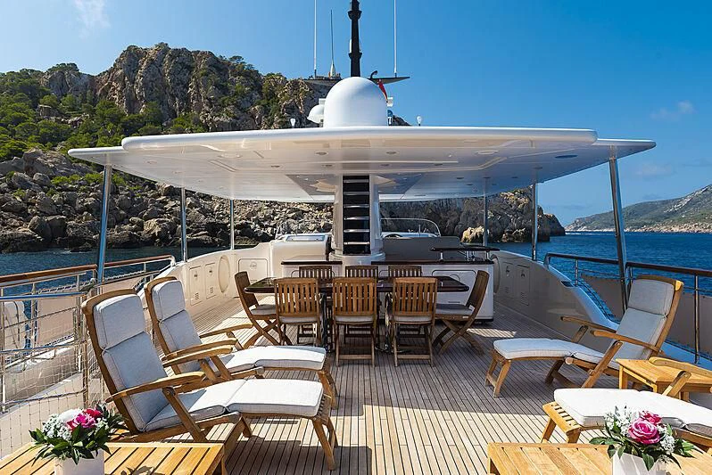 a large white building with a deck and chairs and tables and a body of water aboard LADY ALINA Yacht for Sale
