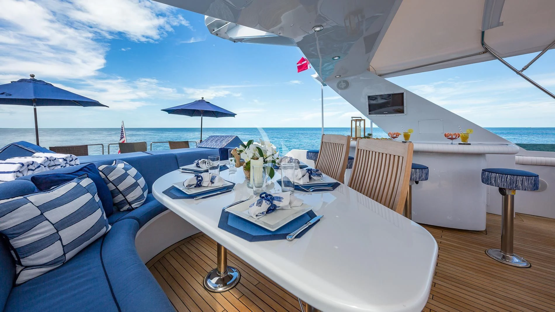 a large white table with blue chairs and umbrellas on it aboard DESTINY Yacht for Sale