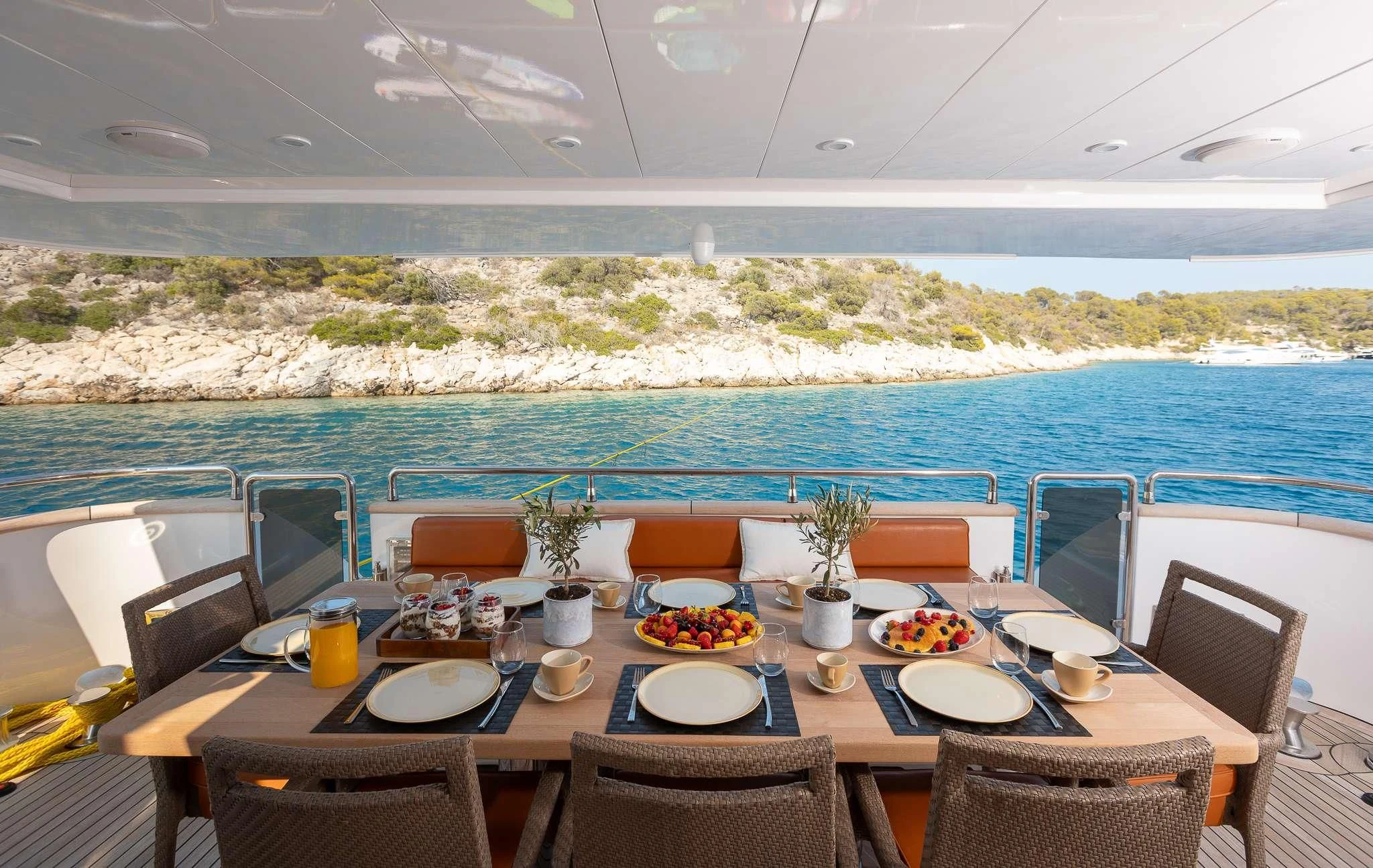 a table set for a meal on a balcony overlooking a large body of water aboard GIOE I Yacht for Sale