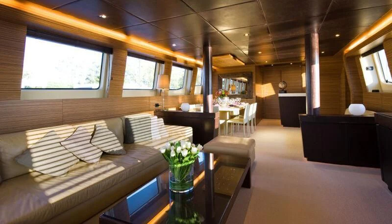 a room with a couch and a table with a vase of flowers aboard GIOE I Yacht for Sale