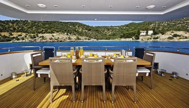 a table set with chairs and a pool in the background aboard GIOE I Yacht for Sale