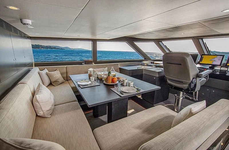 a room with a couch and a table with chairs and a view of the water aboard JANGADA Yacht for Sale