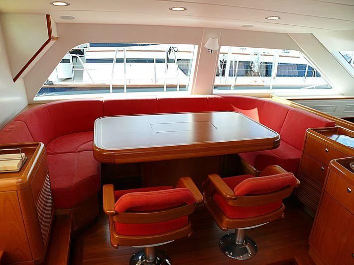 a room with red chairs and a table with a large window aboard NAKUPENDA Yacht for Sale