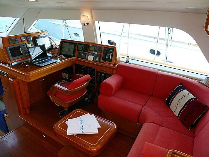a living room with a red couch and a laptop on a table aboard NAKUPENDA Yacht for Sale