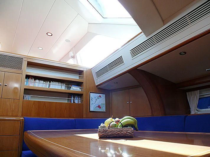 a room with a table and a shelf with books on it aboard NAKUPENDA Yacht for Sale
