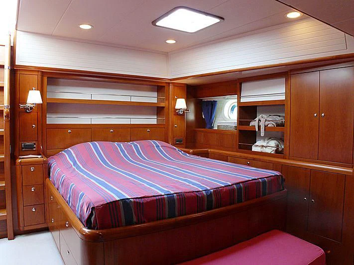 a bedroom with a bed and a dresser aboard NAKUPENDA Yacht for Sale