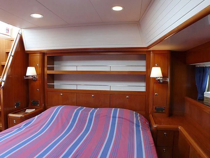 a bed with a purple and white striped blanket aboard NAKUPENDA Yacht for Sale