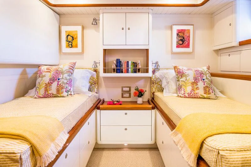 a bedroom with a bed and a shelf with books on it aboard NAKUPENDA Yacht for Sale