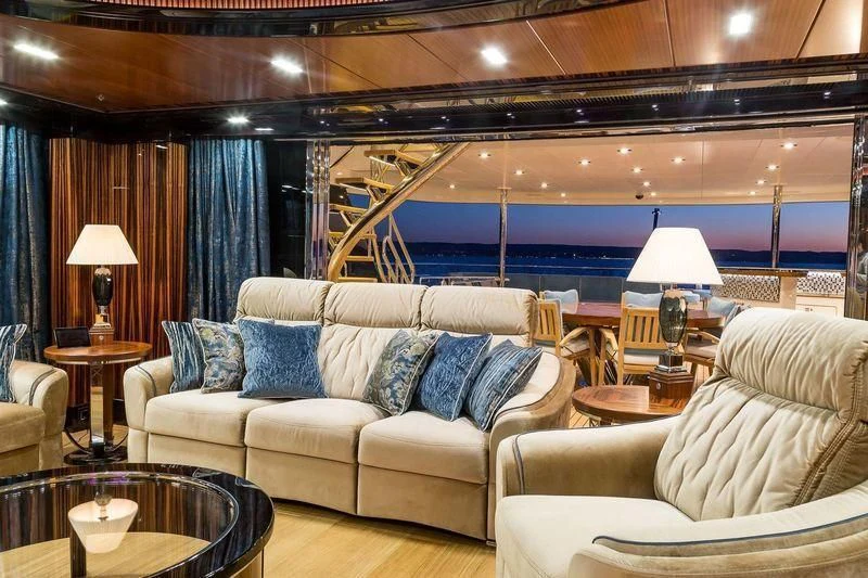a living room with a large blue and white couch and a large window aboard VIATORIS Yacht for Sale
