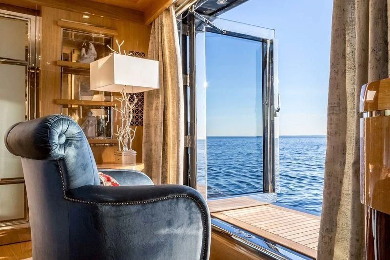 a room with a chair and a table and a window aboard VIATORIS Yacht for Sale