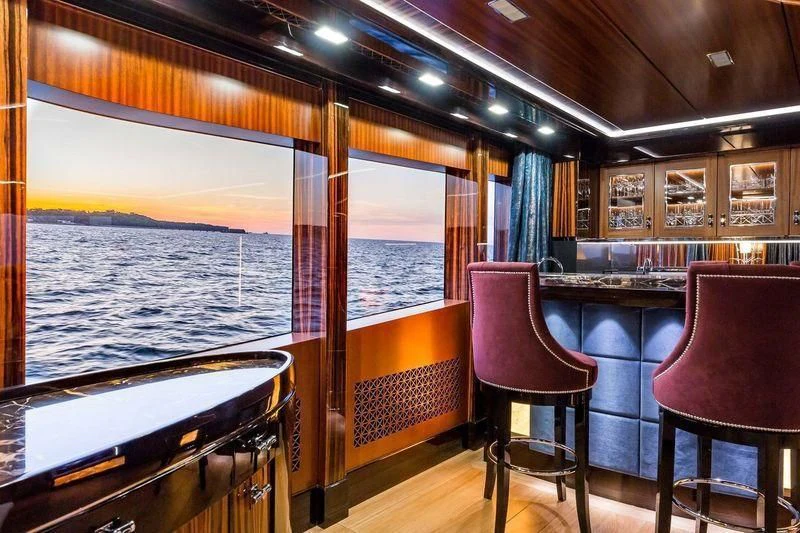 a boat with a chair and a table and chairs in a room with a window aboard VIATORIS Yacht for Sale
