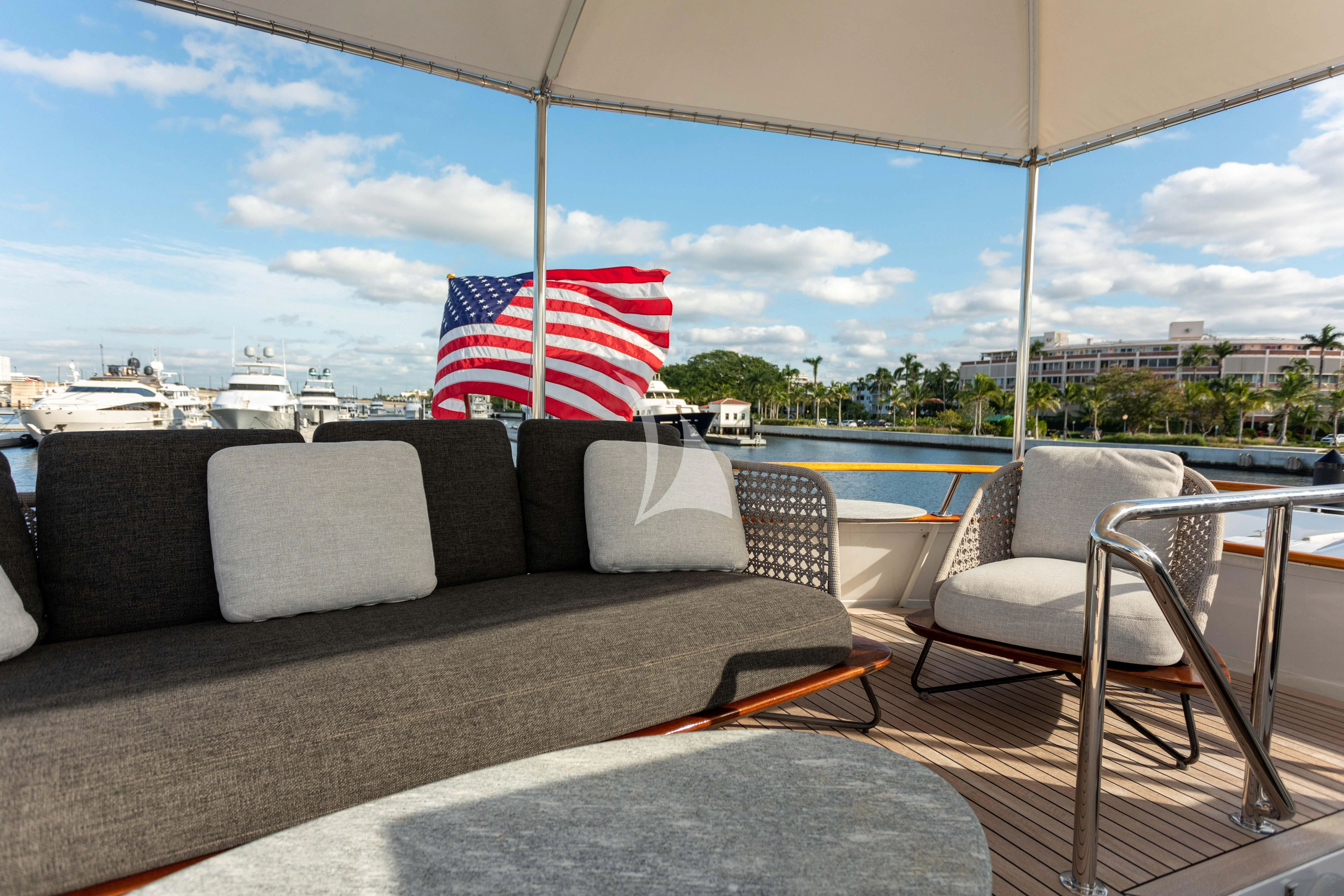 a couch and a chair on a deck with a flag on it aboard SOVEREIGN Yacht for Charter