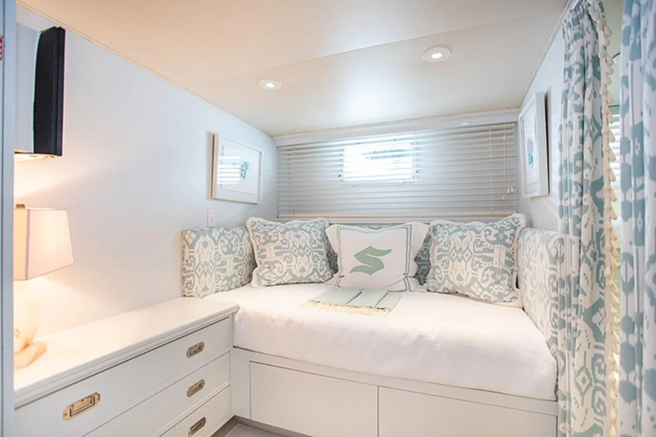 a white couch with a blue and white striped pillow and a white dresser aboard SOVEREIGN Yacht for Charter
