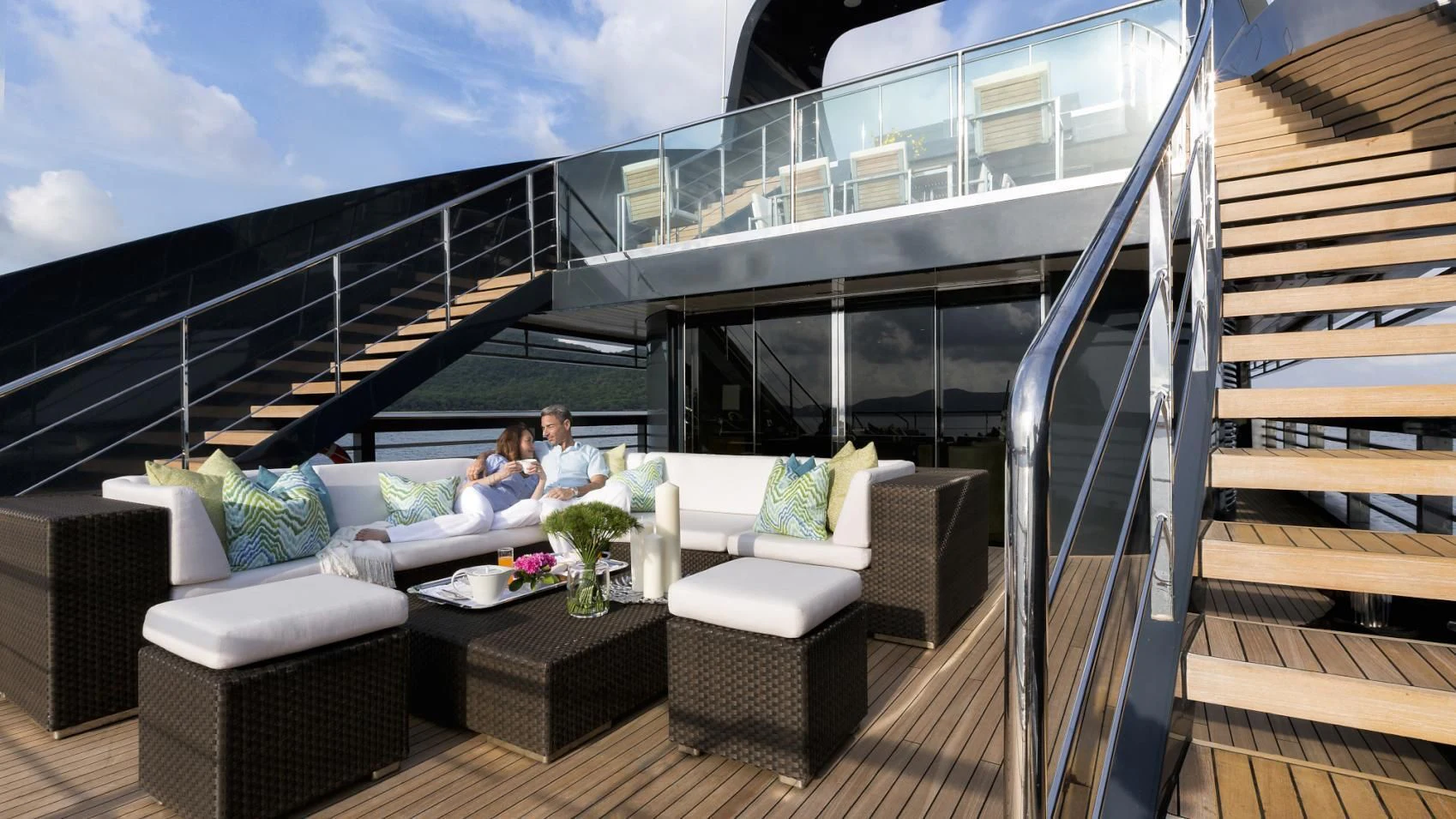 a couple sitting on a couch in a large room with a view of the city below aboard OCEAN EMERALD Yacht for Sale