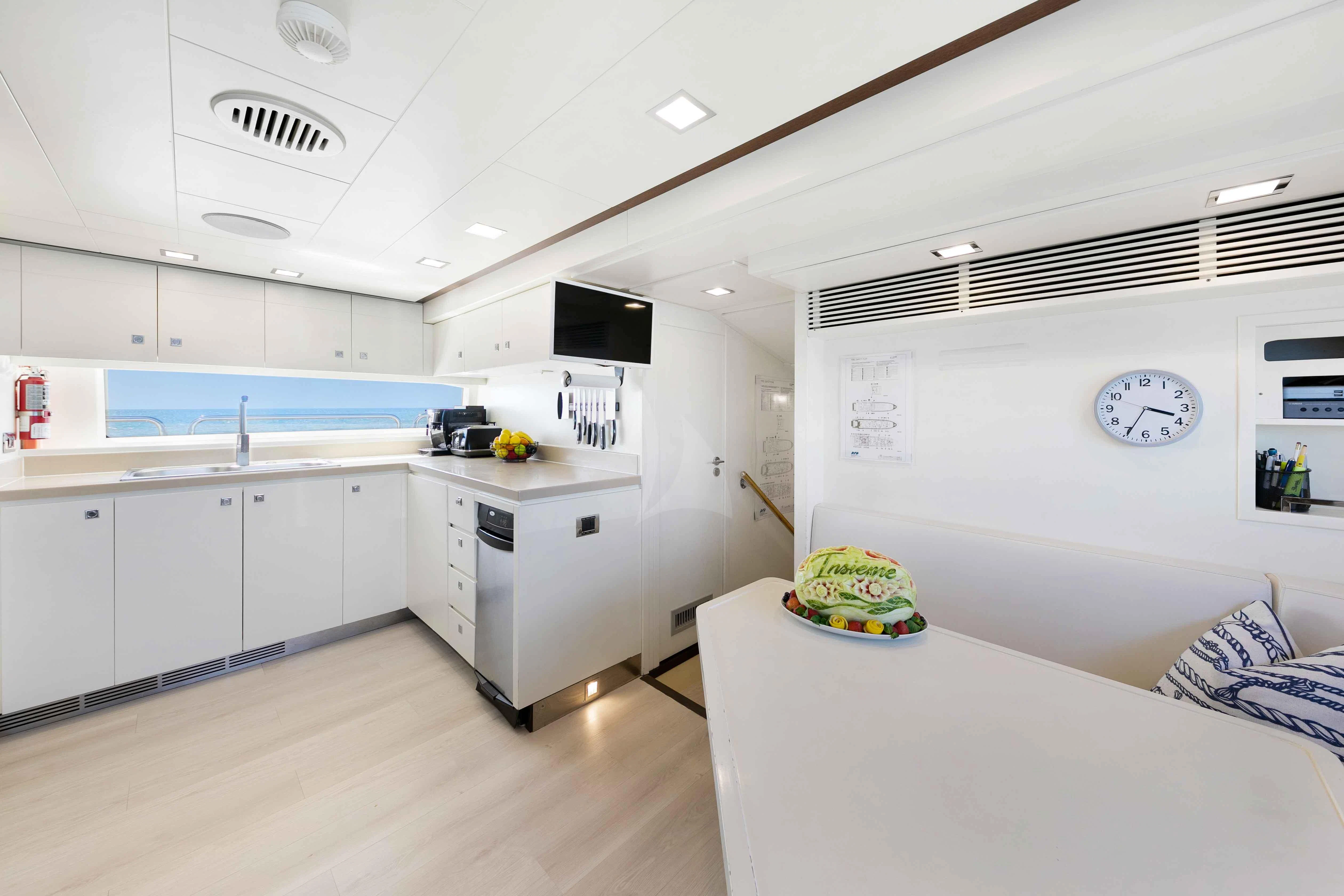 a kitchen with a table and a tv aboard INSIEME Yacht for Sale