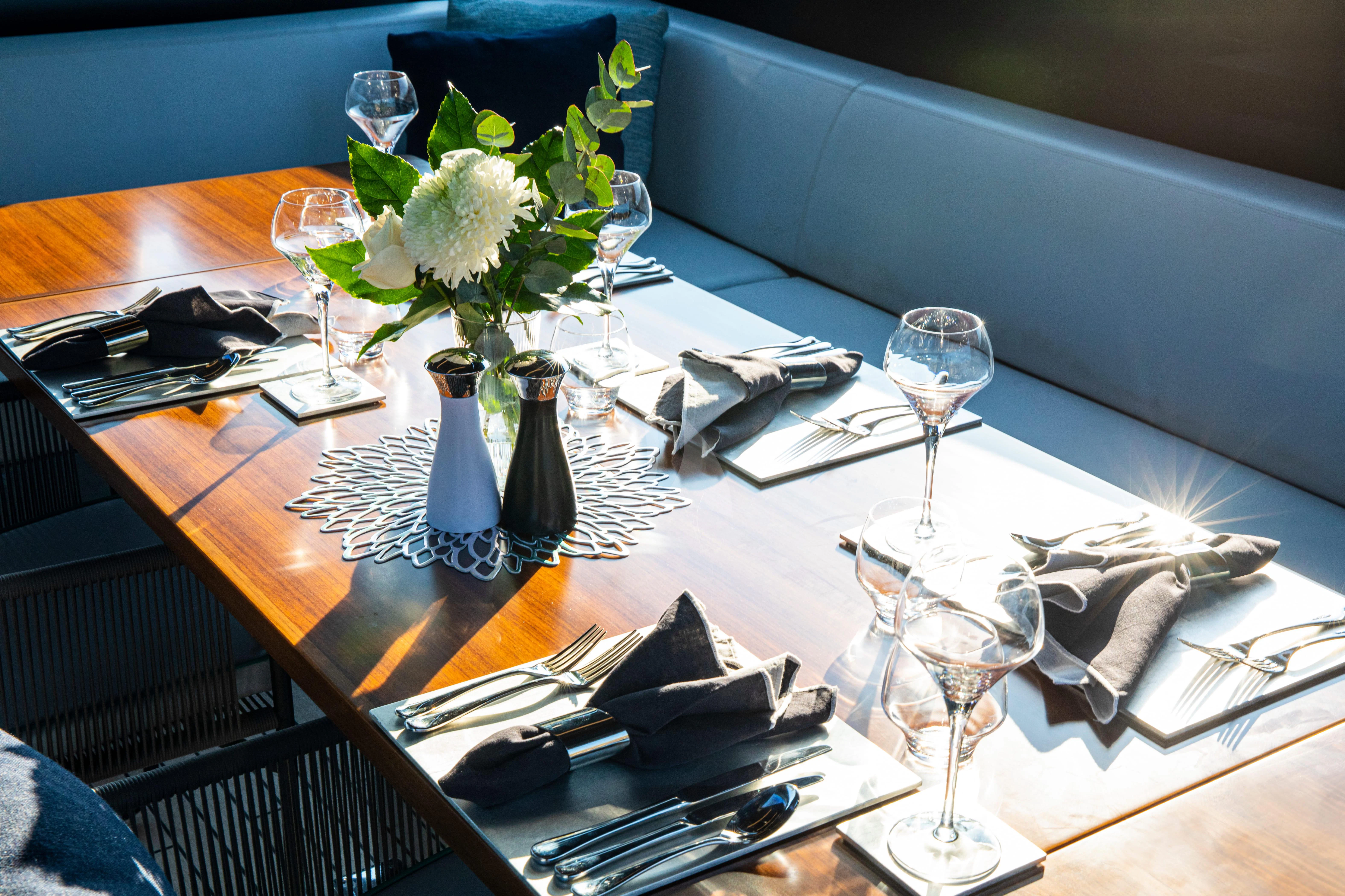 a table with a vase of flowers and glasses on it aboard FIGURATI Yacht for Sale