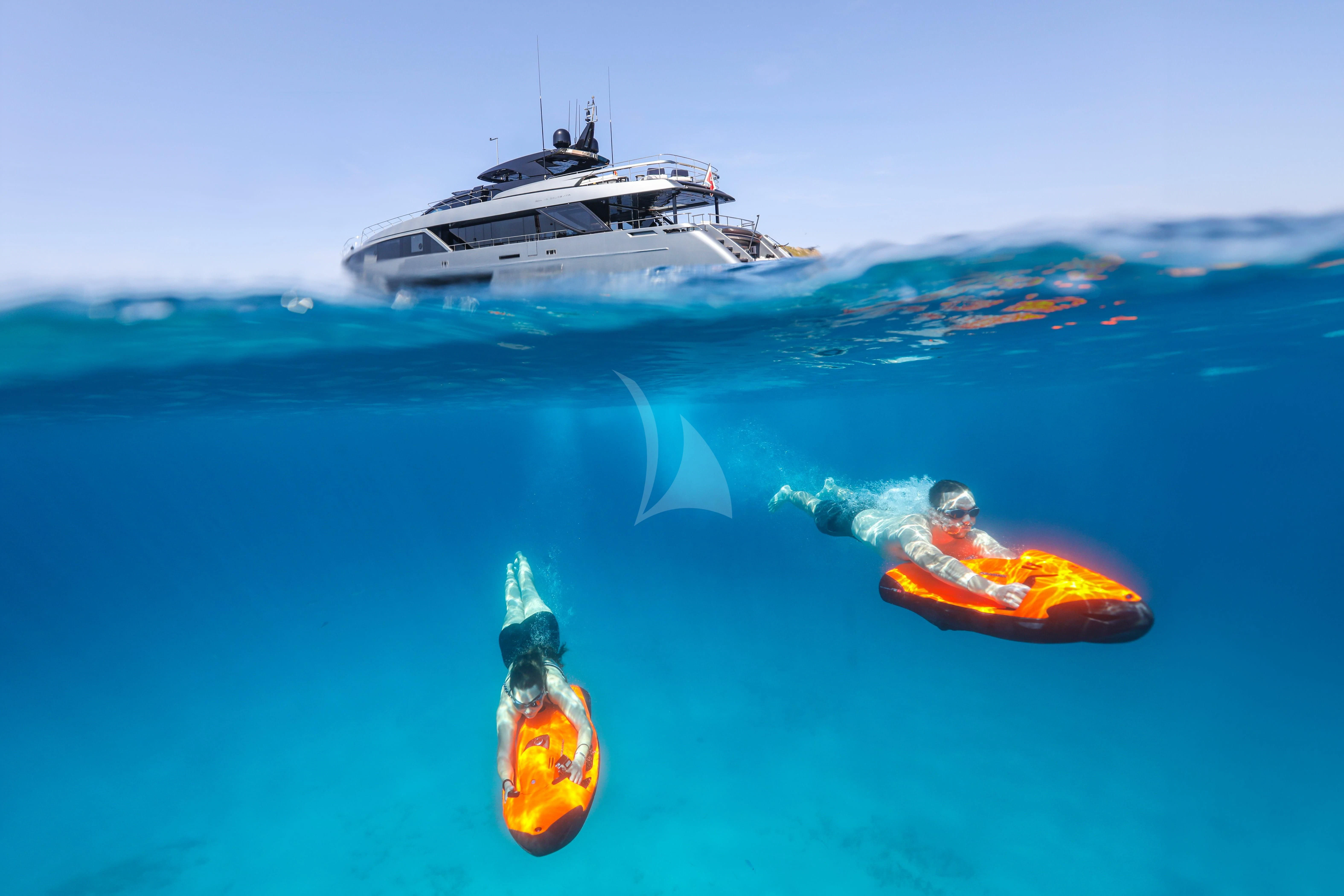 a couple of fish swimming in the ocean with a boat in the background aboard FIGURATI Yacht for Sale