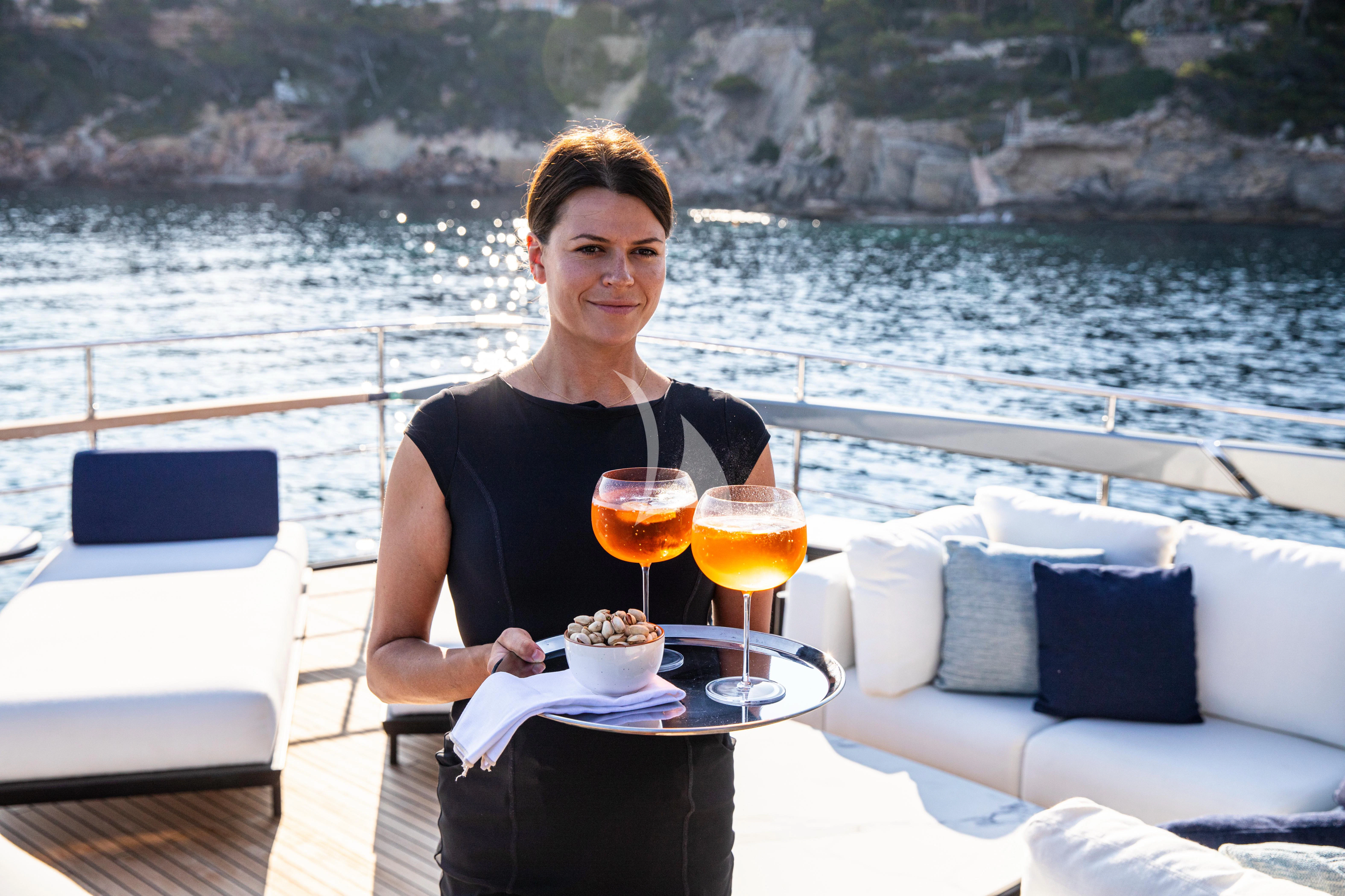 a person holding a tray of food and a glass of juice on a boat aboard FIGURATI Yacht for Sale