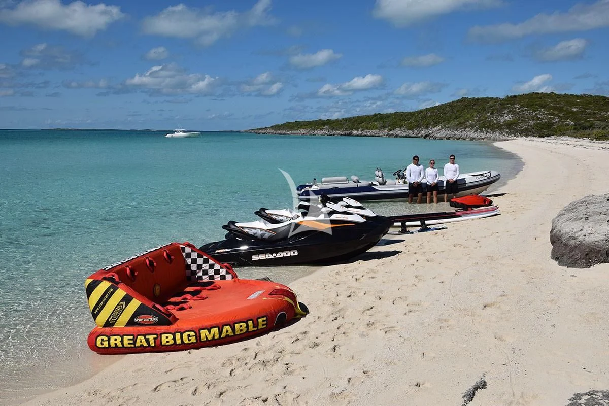 a group of people standing next to a boat on a beach aboard BELLA Yacht for Sale