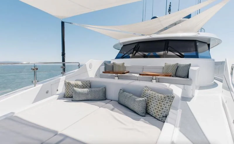 a white lounge chair with a white bed and a large white umbrella on a white patio with a aboard FIGARO Yacht for Sale