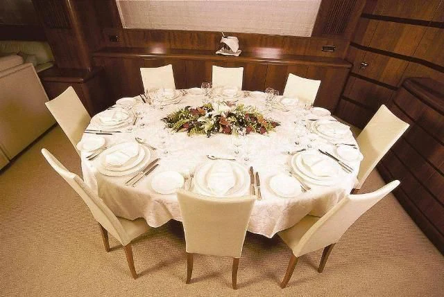 a table set with white plates and flowers aboard ABSOLUTE KING Yacht for Sale