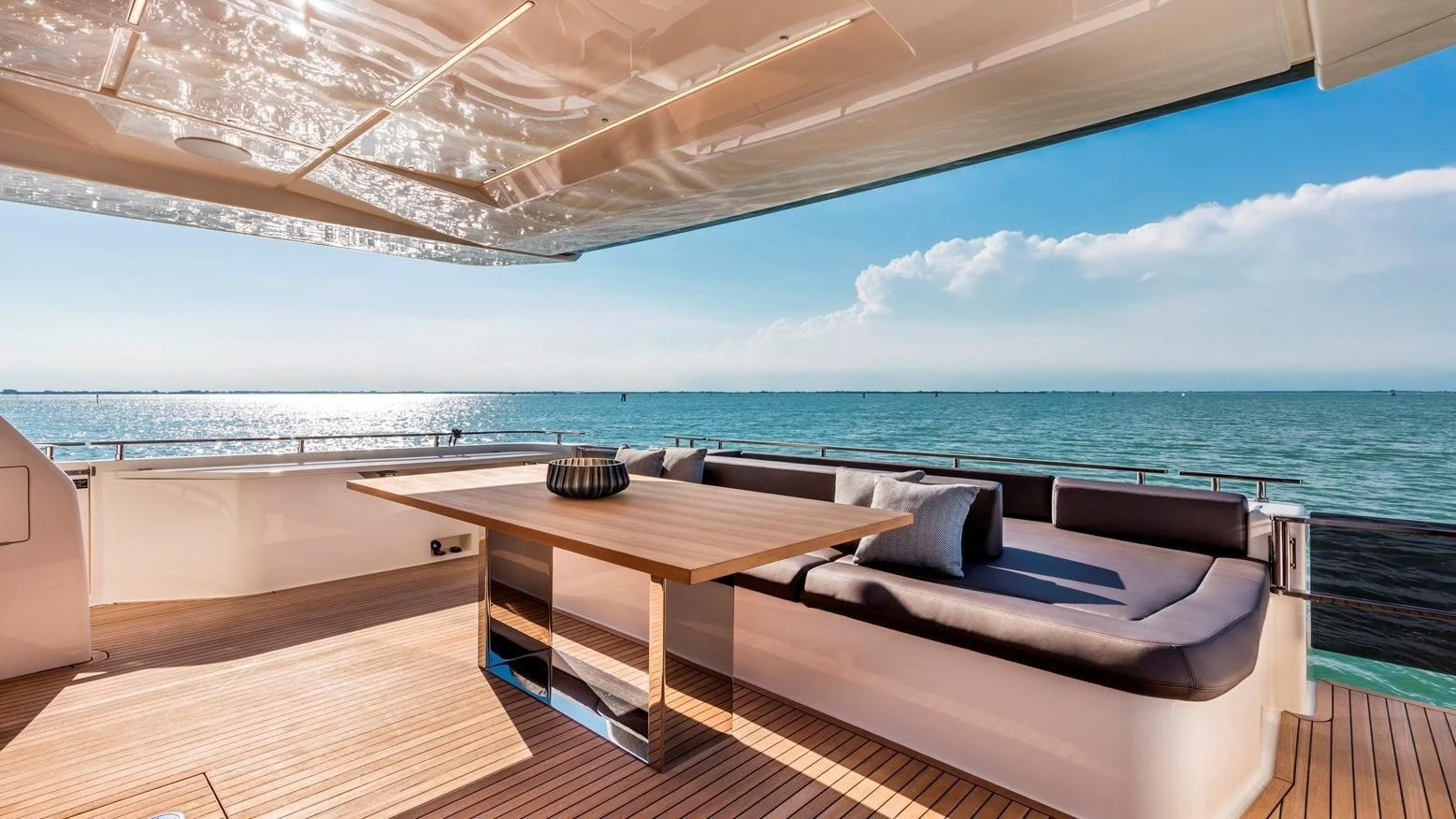 a room with a table and a bed on a deck overlooking the ocean aboard TO INDIA Yacht for Sale