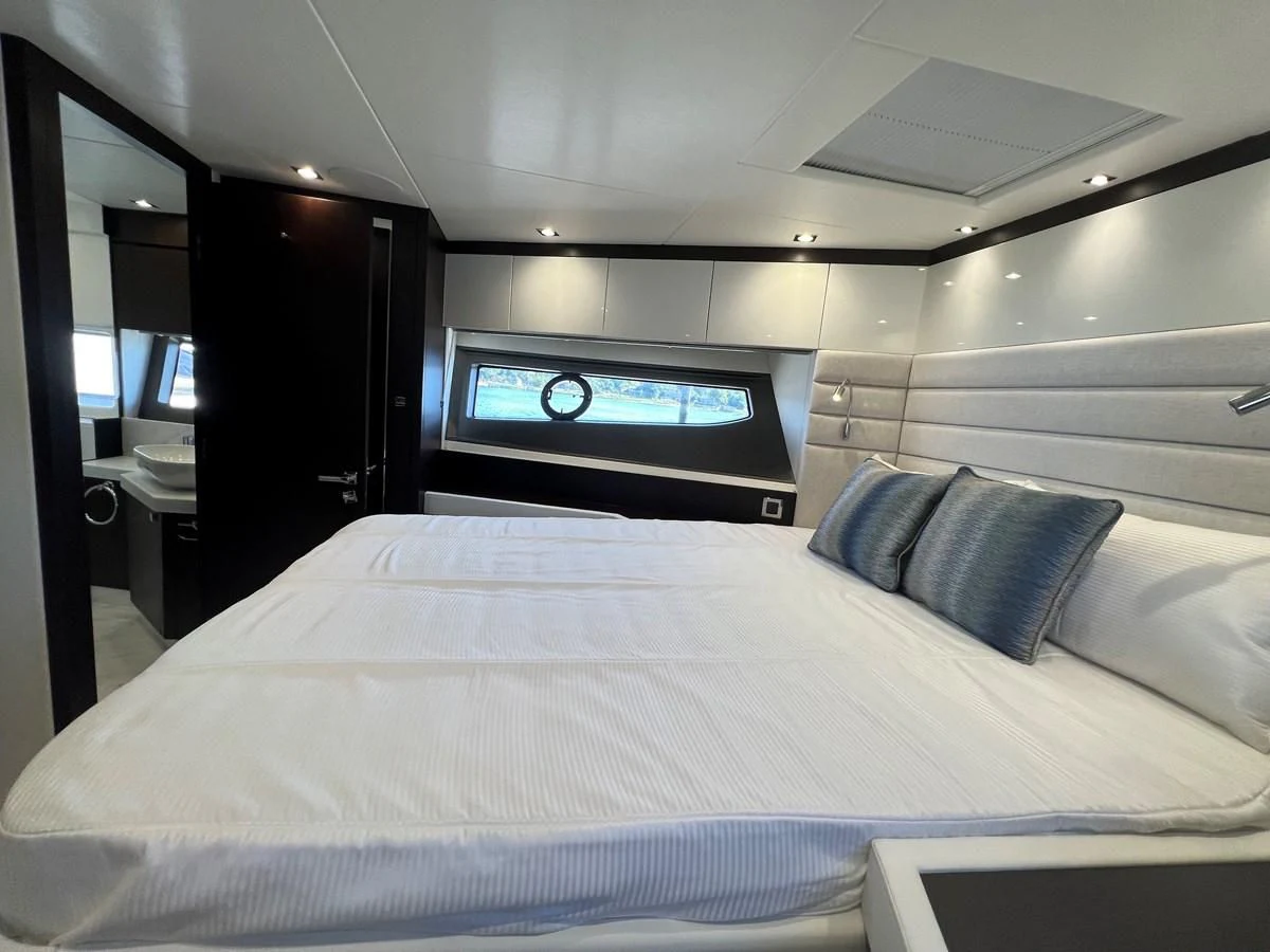 a bed with a white sheet and pillows in a room with a tv aboard 66 MANHATTAN Yacht for Sale