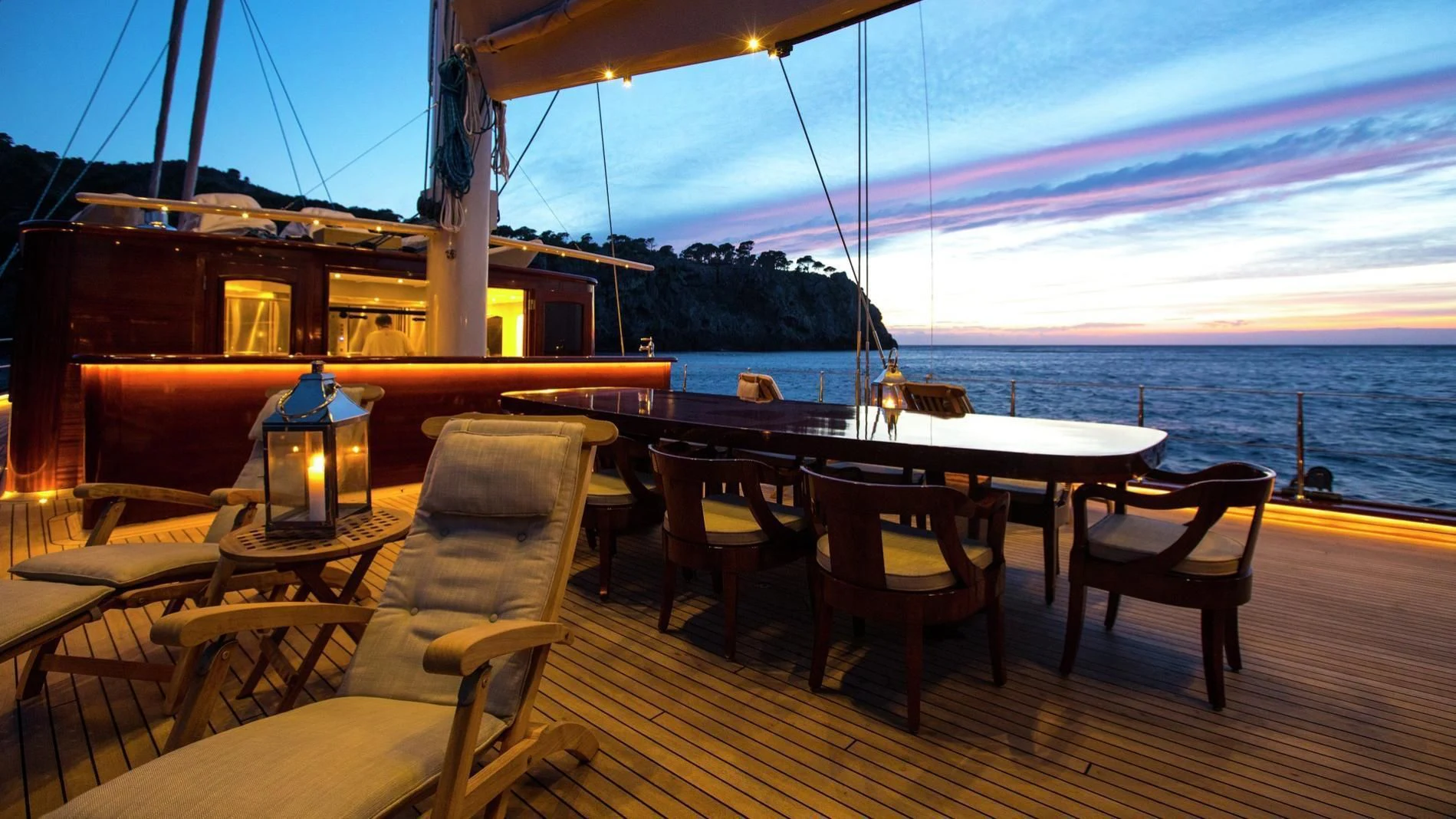 a deck with tables and chairs on it and a body of water in the background aboard NAUTILUS Yacht for Sale