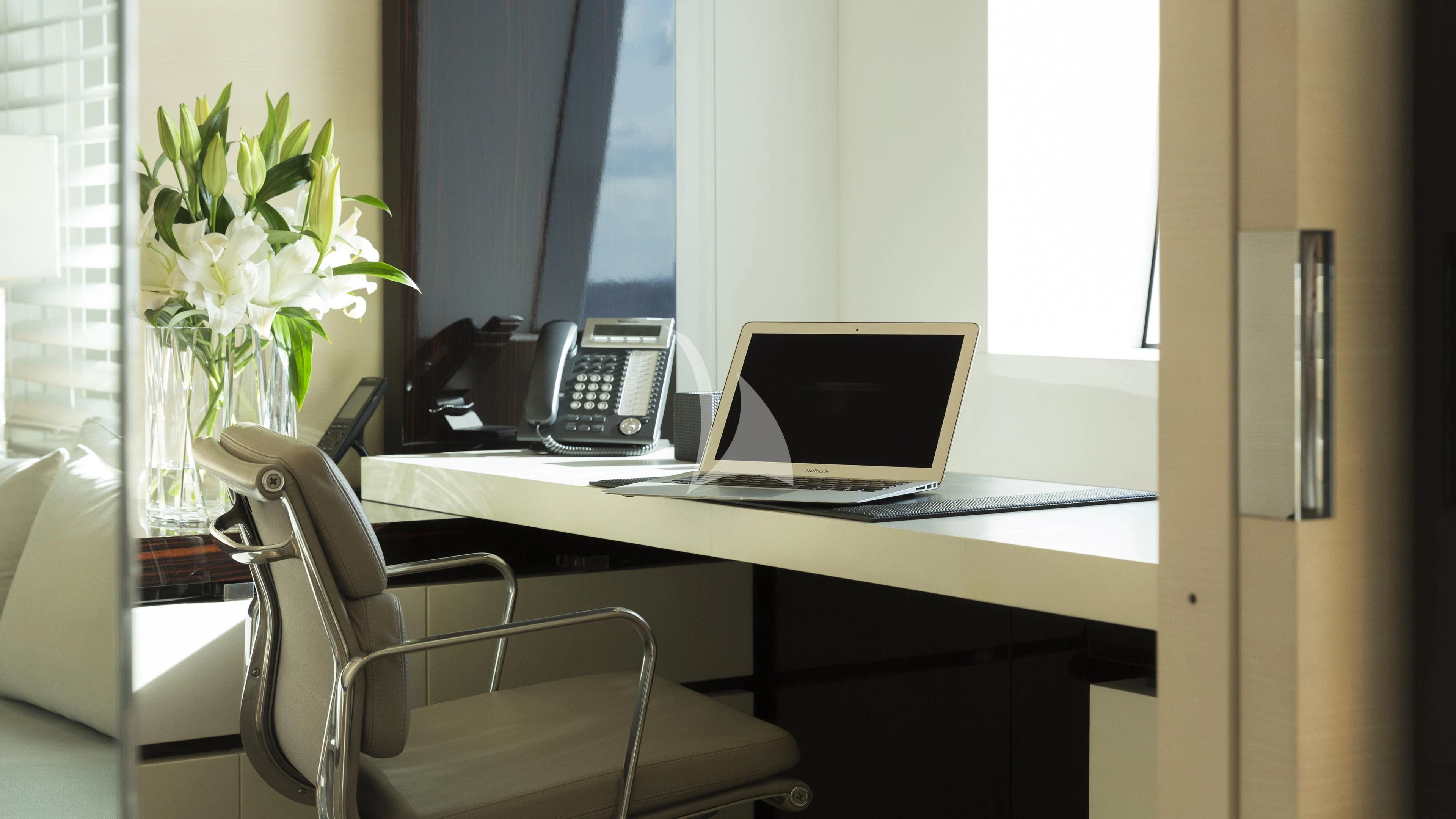 a desk with a laptop and phone on it aboard NAUTILUS Yacht for Sale