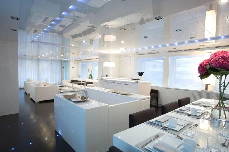 a large room with white cabinets and a table with chairs and flowers aboard FRISH Yacht for Sale