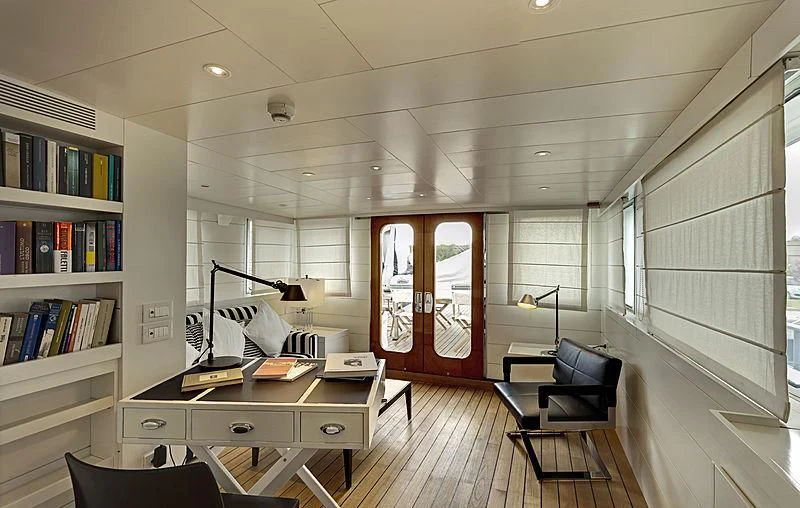 a room with a desk and a chair and a bookcase aboard VERVECE Yacht for Charter